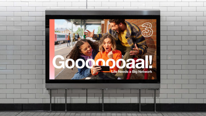 Group of people gathered around phone white text in front of them reads Goooooaaaalll!!