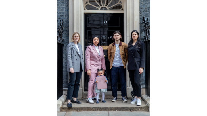 Members of Pregnant Then Screwed standing in front of the door of 10 Downing Street holding a petition.